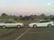 1996 Ford Probe - Two white cars are parked in a lot during twilight with a building in the background.