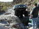 1993 Ford Bronco - A modified Ford Bronco navigates a rocky trail with two onlookers.
