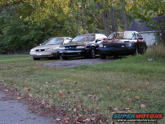 1990 Ford Taurus front view, dark blue, parked with two other cars