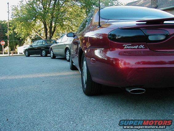 Rear of a red 1990 Ford Taurus GL with two other cars behind it
