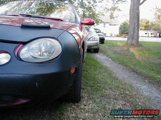 1990 Ford Taurus front end with car cover, parked behind another car