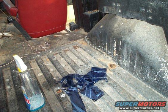 Truck bed interior with red seat, spray bottle, and blue plastic wrap