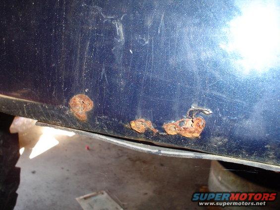 Rust spots on the lower body panel of a dark blue vehicle