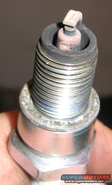 Spark plug with worn electrode held by a hand