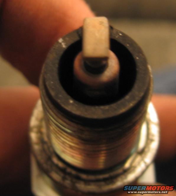 Close-up of a spark plug held by a finger