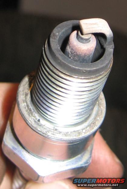 Close-up of a used spark plug held by a hand