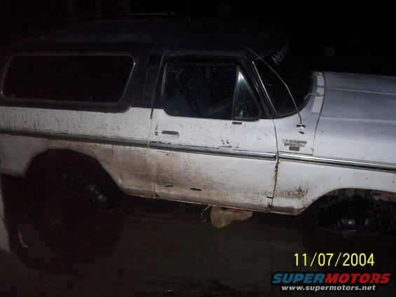 White and black Ford Bronco, dirty, side view, with visible chrome trim and a dark roof