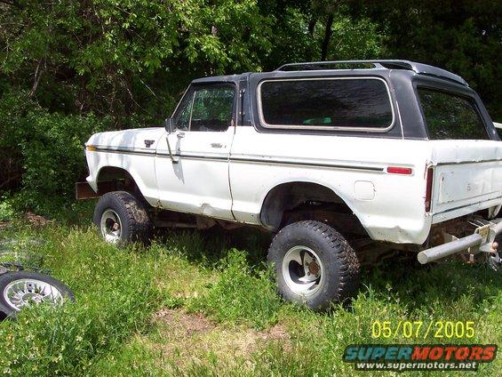 White 1978 Ford Bronco with black top, lifted, parked in grassy area, side view