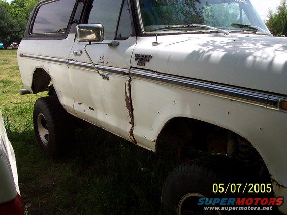 White Ford Bronco, lifted, with visible rust on the driver's side door and fender