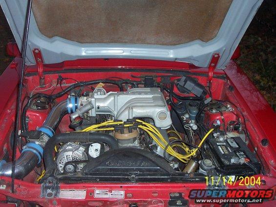 Red car engine bay with silver intake and yellow spark plug wires