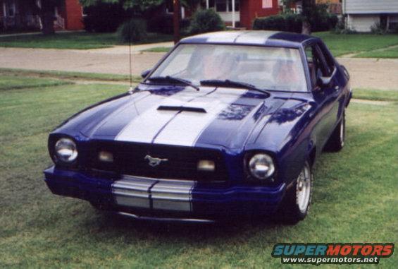 Blue 1977 Ford Mustang II with silver racing stripes parked on grass