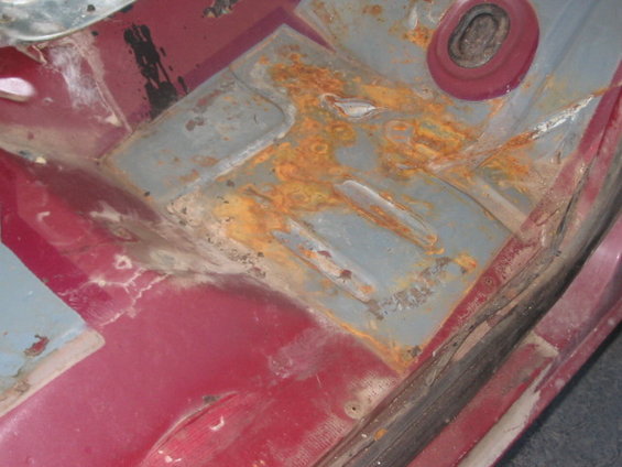rusted floor pan with some red paint visible