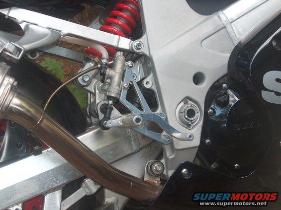 Motorcycle rear brake assembly and exhaust with visible "SUZUKI" text