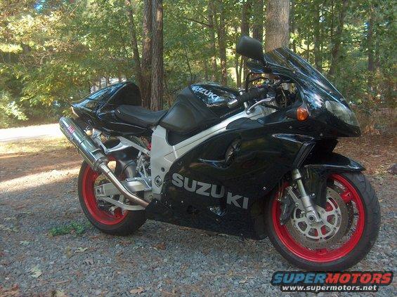 Black 2002 Suzuki TL1000R motorcycle with red wheels parked on gravel