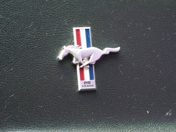 Ford Mustang 25th Anniversary badge with a running horse emblem and "25 YEARS" text on a textured dark surface