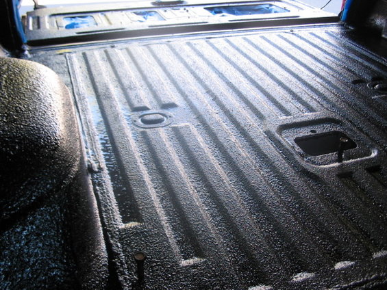Black textured cargo floor with ribbed metal and tie-down points