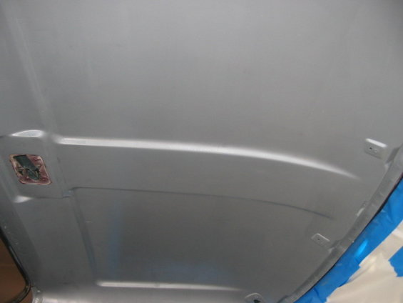 Underside of gray car hood with latch mechanism visible
