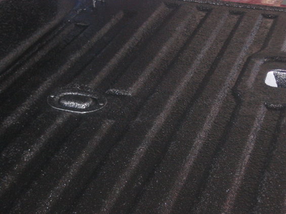 Black textured truck bed liner with tie-down anchor