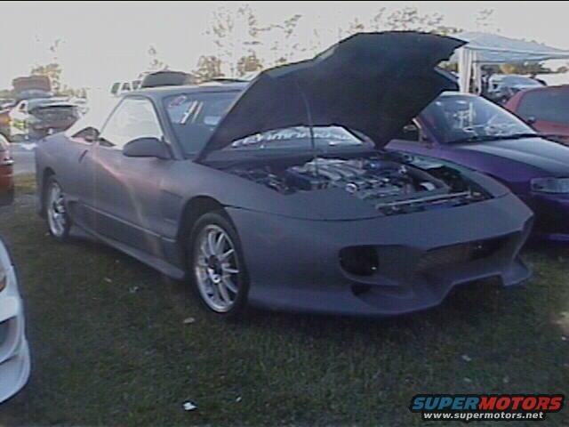 1994 Ford Probe with hood open, showing engine bay. Parked on grass with other cars nearby
