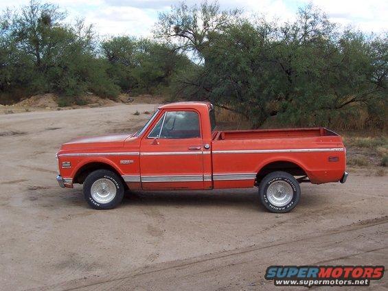 Orange pickup truck with chrome trim and aftermarket wheels parked on a dirt road