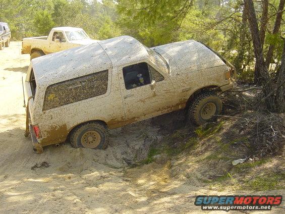 Muddy SUV stuck on a dirt hill with another truck behind it
