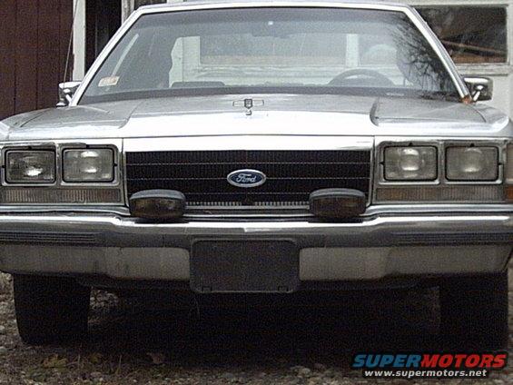 Front view of a silver Ford Crown Victoria with a black grille and two fog lights