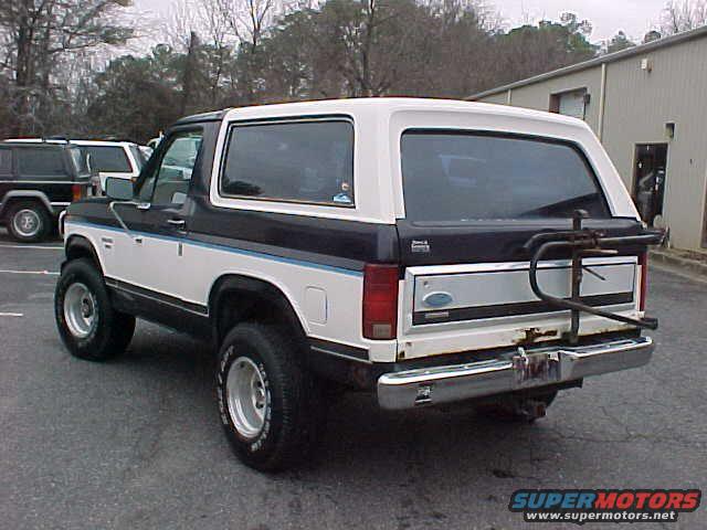 Two-tone Ford Bronco with a bike rack on the rear, parked next to other SUVs