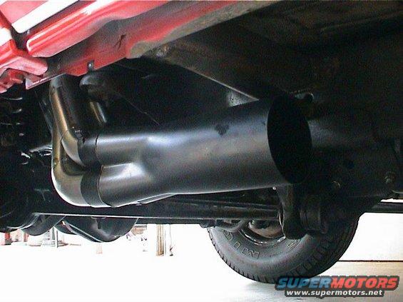 underneath view of a vehicle's exhaust headers and pipe, with a tire visible
