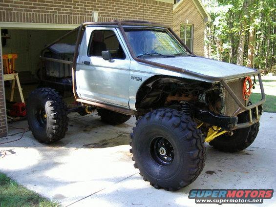 Silver pickup truck with roll cage and oversized tires