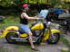 1998 Suzuki VL 1500 Intruder Classic - A man sits on a yellow motorcycle parked outdoors with trees and a car in the background.