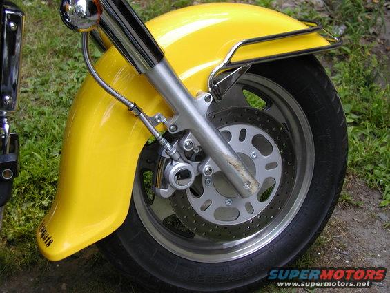 Close-up of a yellow motorcycle's front fender, wheel, and brake assembly. Text on fender reads 'Hogwarts'