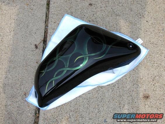 Black motorcycle fender with green flame graphics, resting on a white microfiber towel