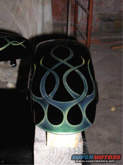 Black motorcycle fender with green and blue flame-like pinstriping, angled view