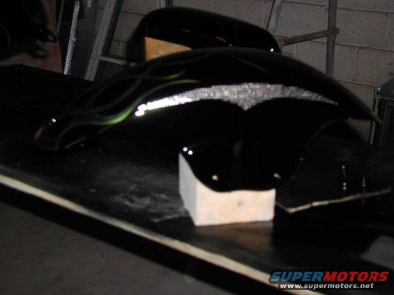 Black motorcycle fender with green and yellow flames and a silver tribal design