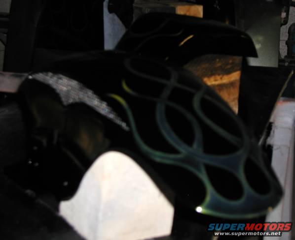 Black motorcycle fender with green and yellow flame graphics, partially visible
