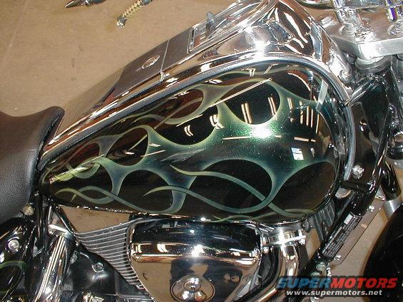 Motorcycle fuel tank with green and black flame paint job. Chrome accents visible