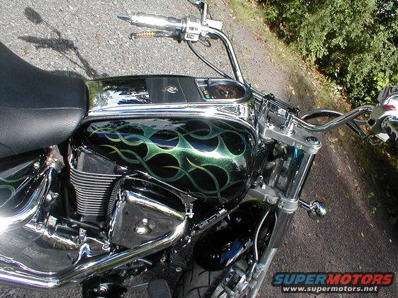 Motorcycle with black fuel tank painted with green flames, chrome handlebars, and black seat