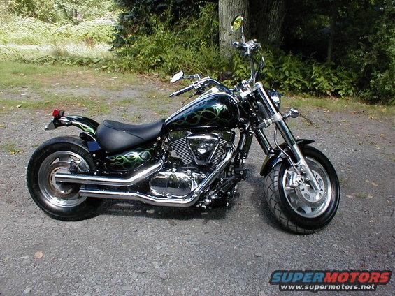 Black motorcycle with green flame graphics, parked on gravel