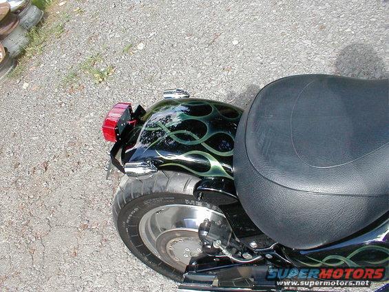 Motorcycle rear fender with green flames paint and black seat. Tire and taillight visible