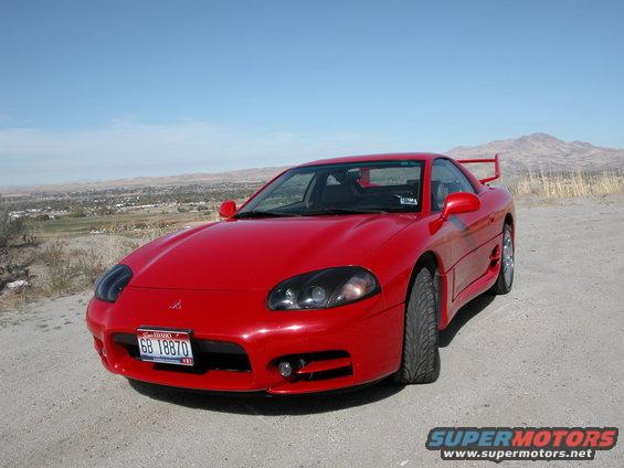 red Mitsubishi 3000GT parked on dirt road with mountains in background