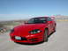 1999 Mitsubishi 3000GT - A red 1999 Mitsubishi 3000GT is parked outdoors with a scenic mountain landscape behind it.