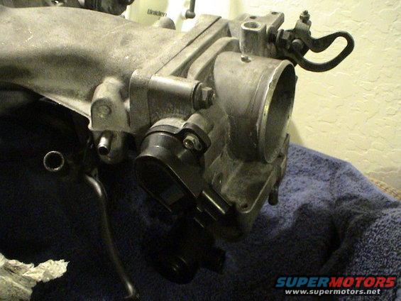 Close-up of a throttle body assembly with linkages and sensors