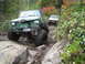 1990 Ford Bronco - Two modified off-road vehicles navigate a challenging rocky trail during autumn.