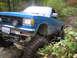 1990 Ford Bronco - This blue pickup truck, likely from the early 1990s, navigates a challenging off-road course with its large, aggressive tires.