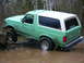 1990 Ford Bronco - This 1990 Ford Bronco is navigating a muddy off-road trail, with one wheel on a large rock.
