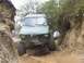 1990 Ford Bronco - Off-road vehicle navigating a challenging dirt path with steep embankments on either side.