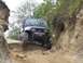 1990 Ford Bronco - A Jeep Wrangler navigates a challenging off-road path with steep, eroded sides.