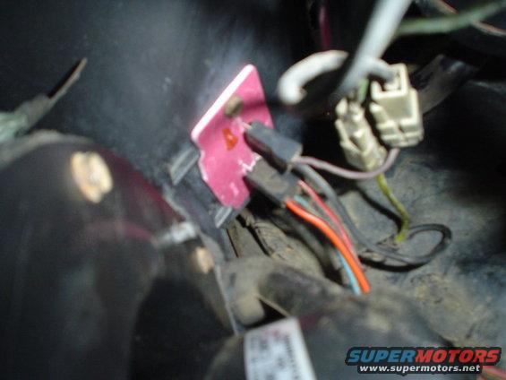 close-up of vehicle wiring harness with pink connector and orange, red, and blue wires