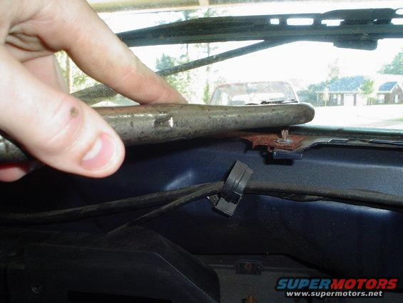 Interior dashboard with a hand pointing to a metal rod near the windshield