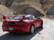 1999 Mitsubishi 3000GT - Rear view of a red 1999 Mitsubishi 3000GT sports car on a dirt road.